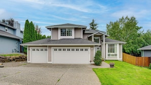 A two-story residential house with a garage, a small front yard, and a wooden fence. - Washington Retreat w/ Yard - Near Seattle! (Marysville)