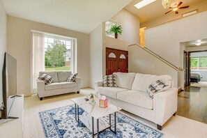 A living room with two sofas, a coffee table, and a TV. There is a staircase leading to an upper level.