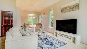 A living room with a sofa, two armchairs, a coffee table, a TV on a stand, and a large window with a view of greenery. - Washington Retreat w/ Yard - Near Seattle! (Marysville)