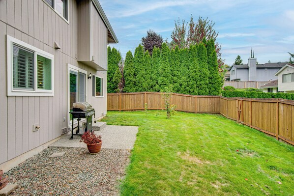 A residential backyard with a wooden fence, a lawn, and a potted plant.