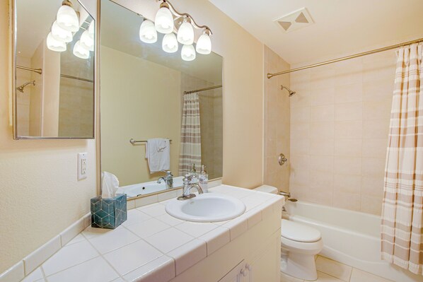 Un baño con lavamanos blanco, un espejo, un inodoro y una ducha con cortina.