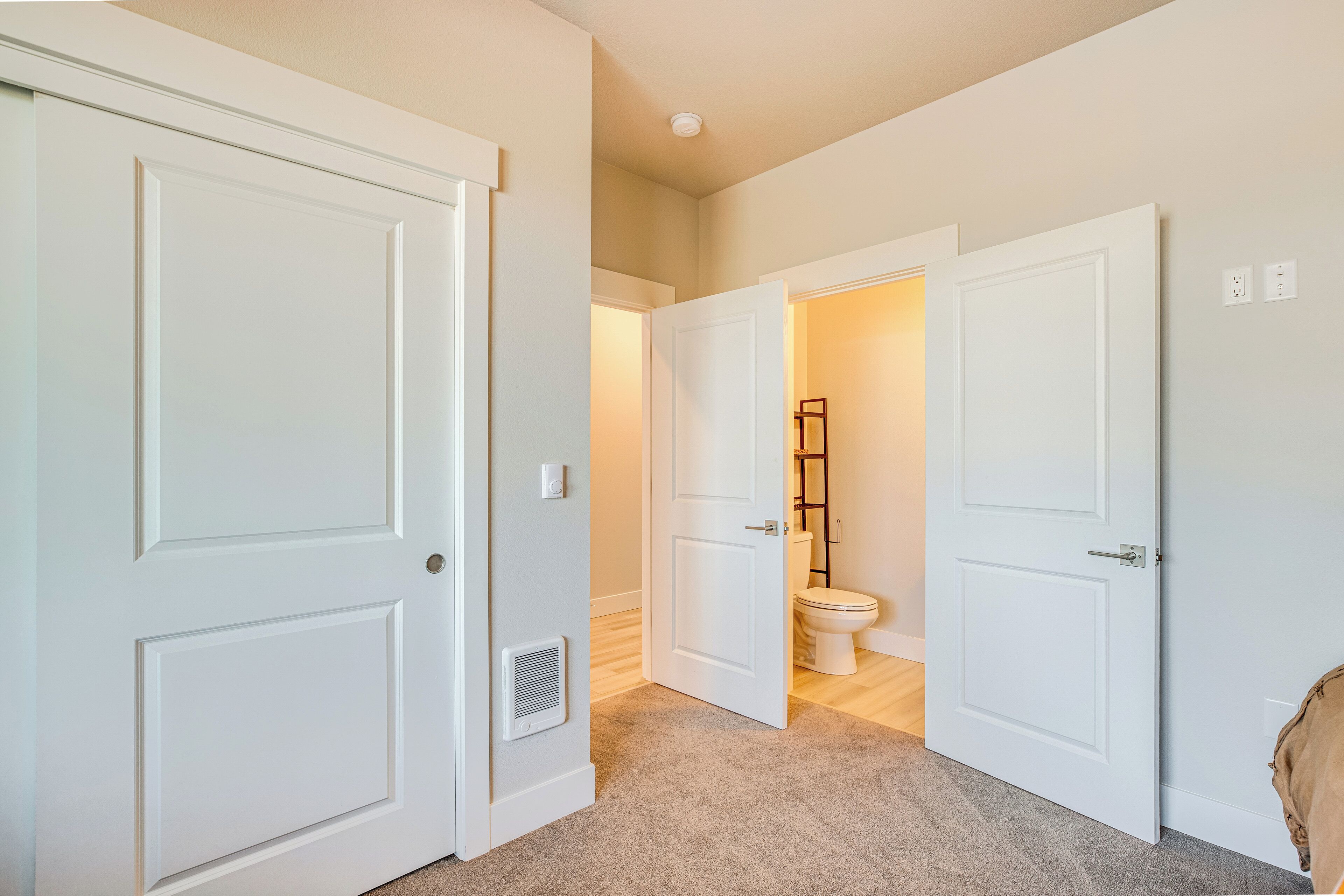 A hallway with white doors leading to a bathroom.