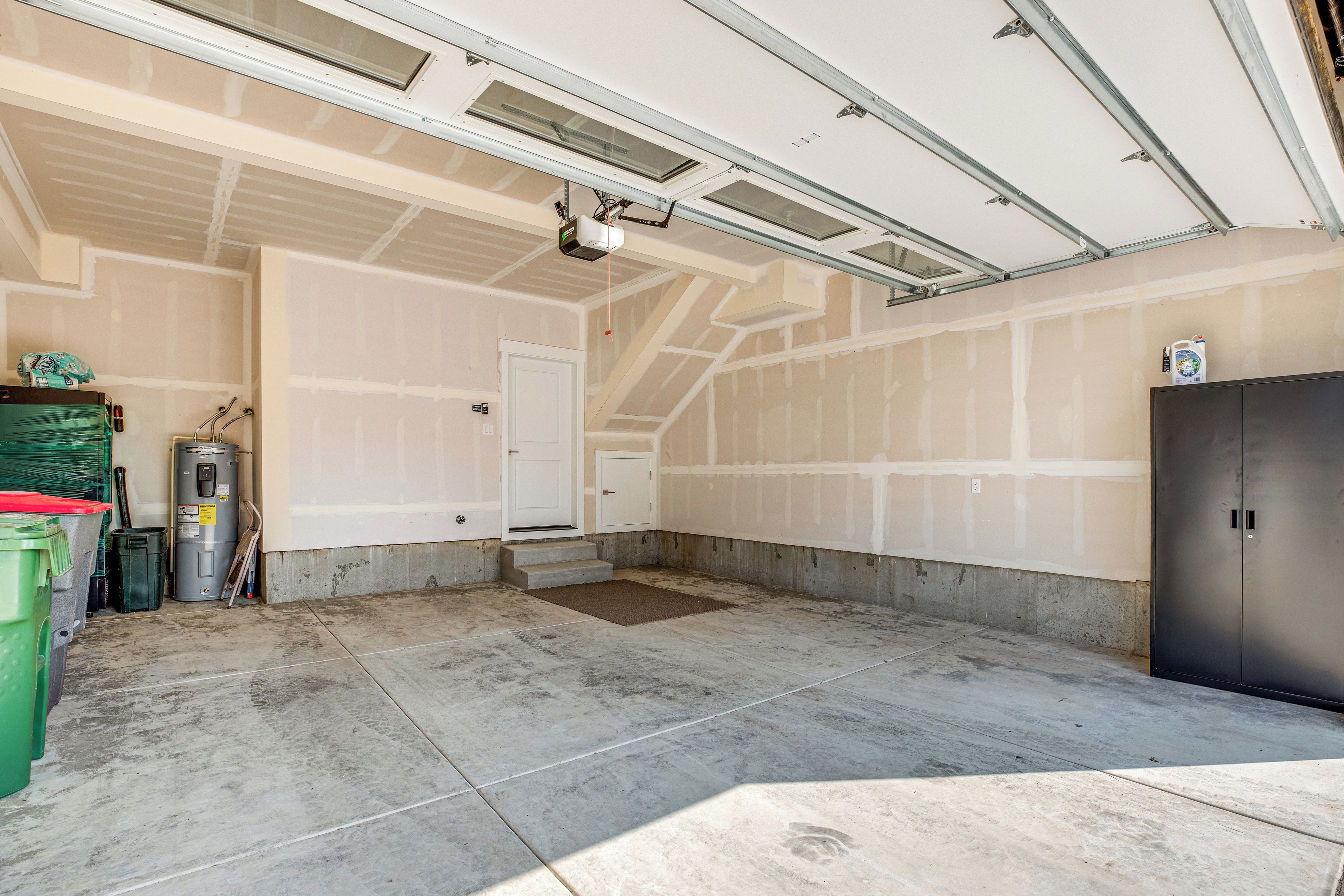A garage with a concrete floor, a white door, and a black cabinet.