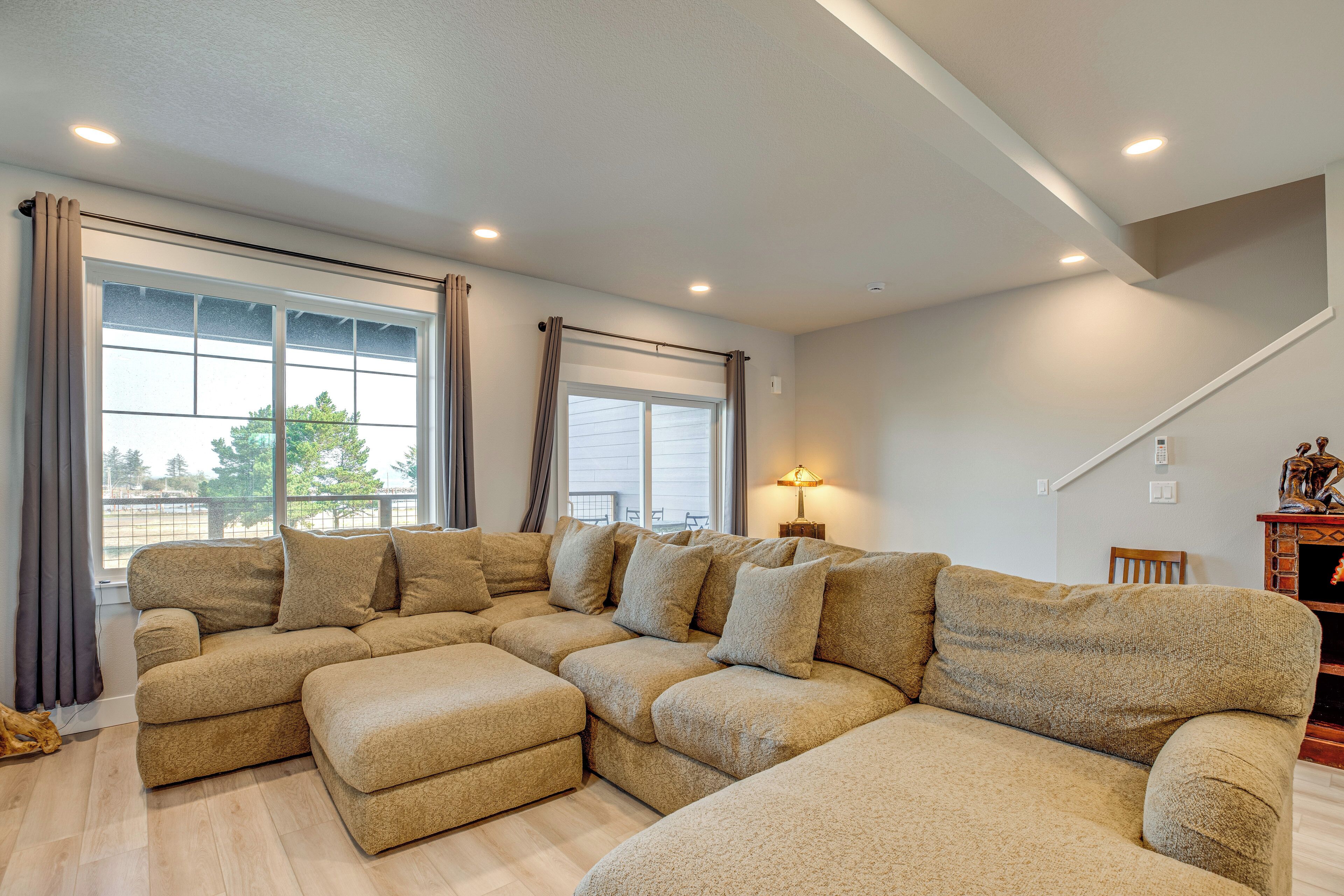 A large sectional sofa with multiple cushions, a wooden floor, and a staircase in the background.