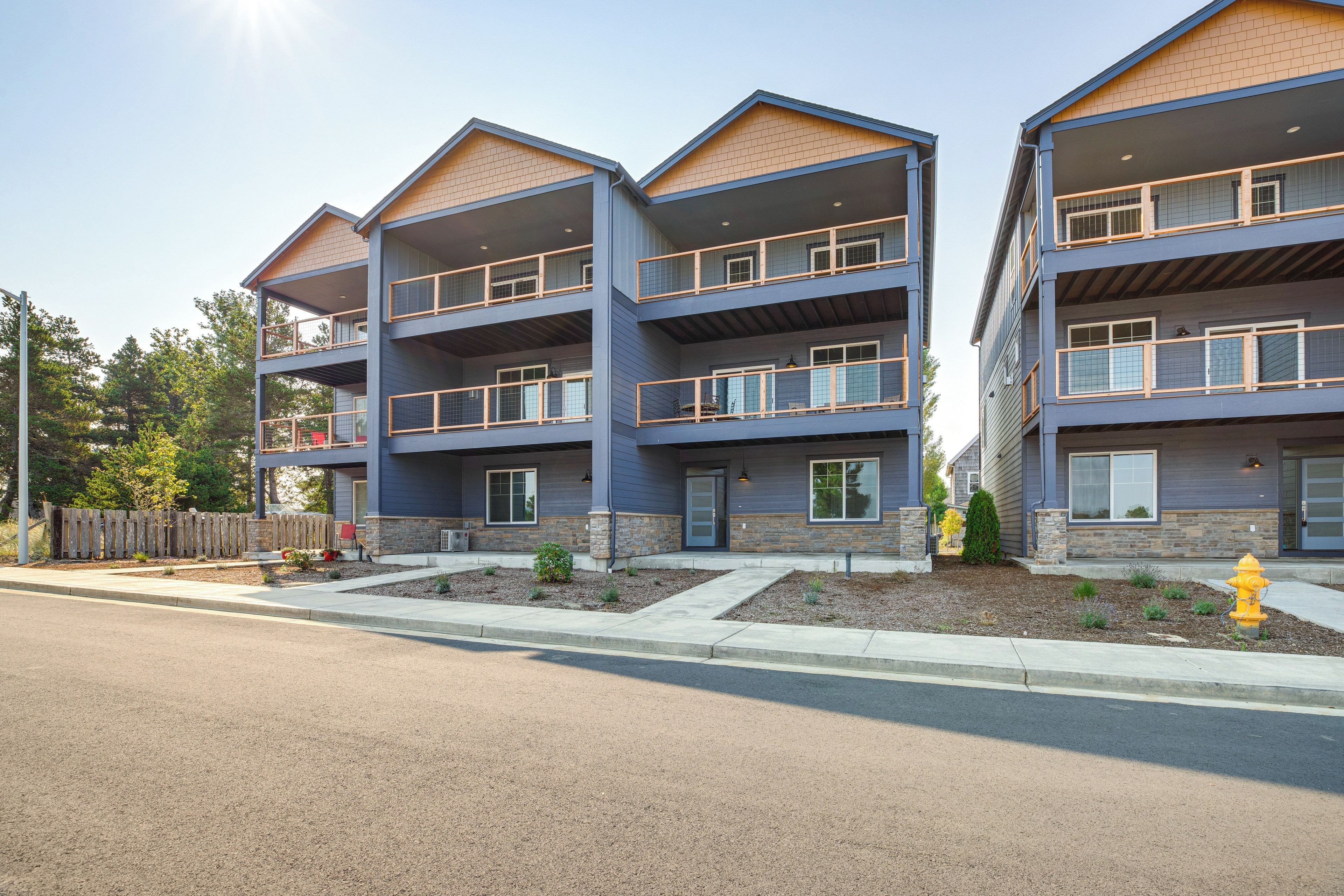 A multi-story residential building with balconies, a fire hydrant, and a clear sky.