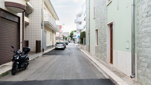 A narrow street lined with residential buildings, a parked motorcycle, and a few cars. - The Flower House by Wonderful Italy (Bitritto)
