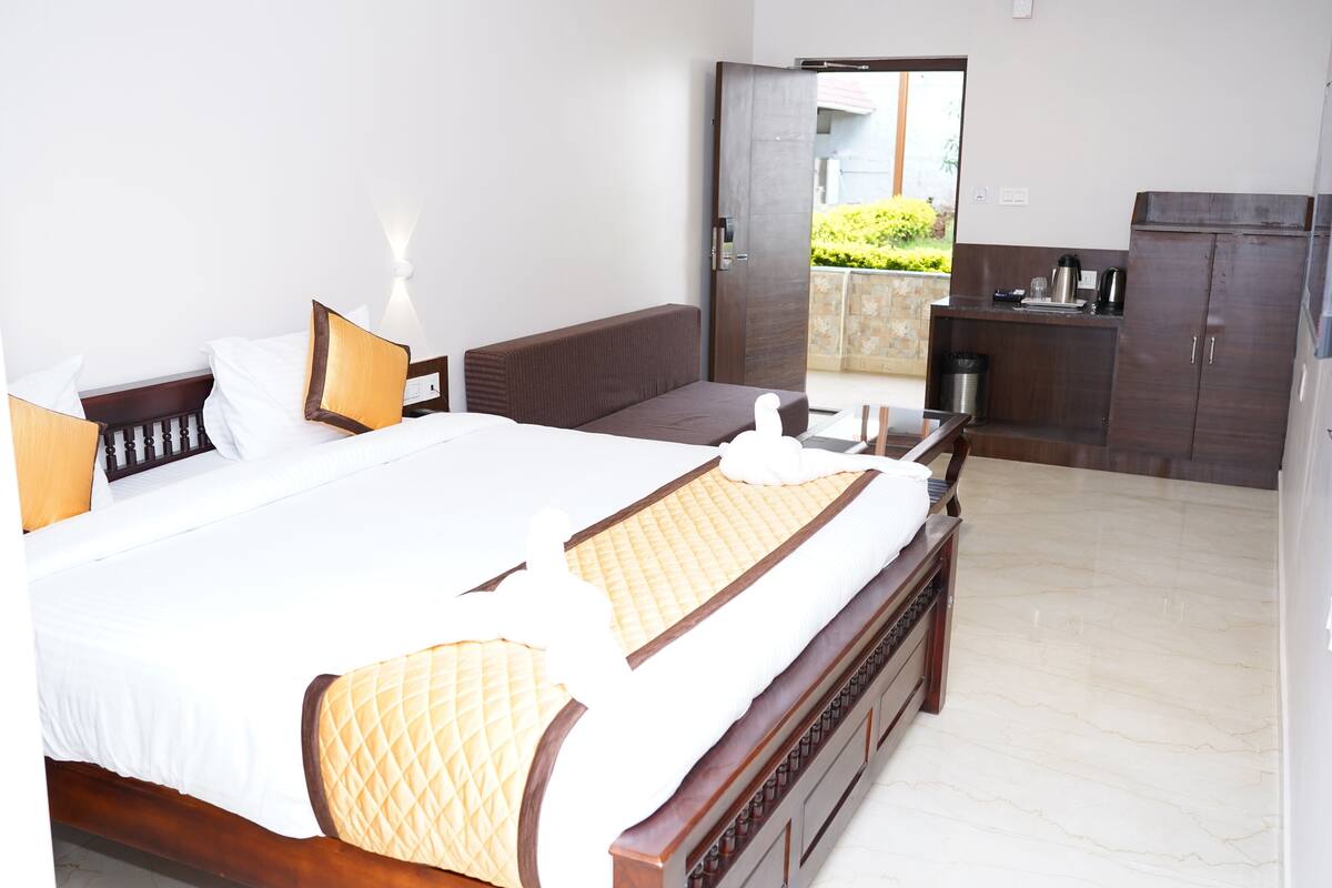 Une chambre d’hôtel avec un grand lit, une tête de lit en bois, une table de chevet, une commode, une armoire et une vue sur l’extérieur.
