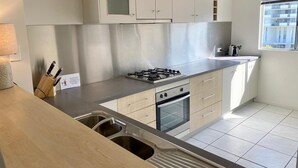 Una cocina moderna con estufa a gas, horno y pileta de acero inoxidable.