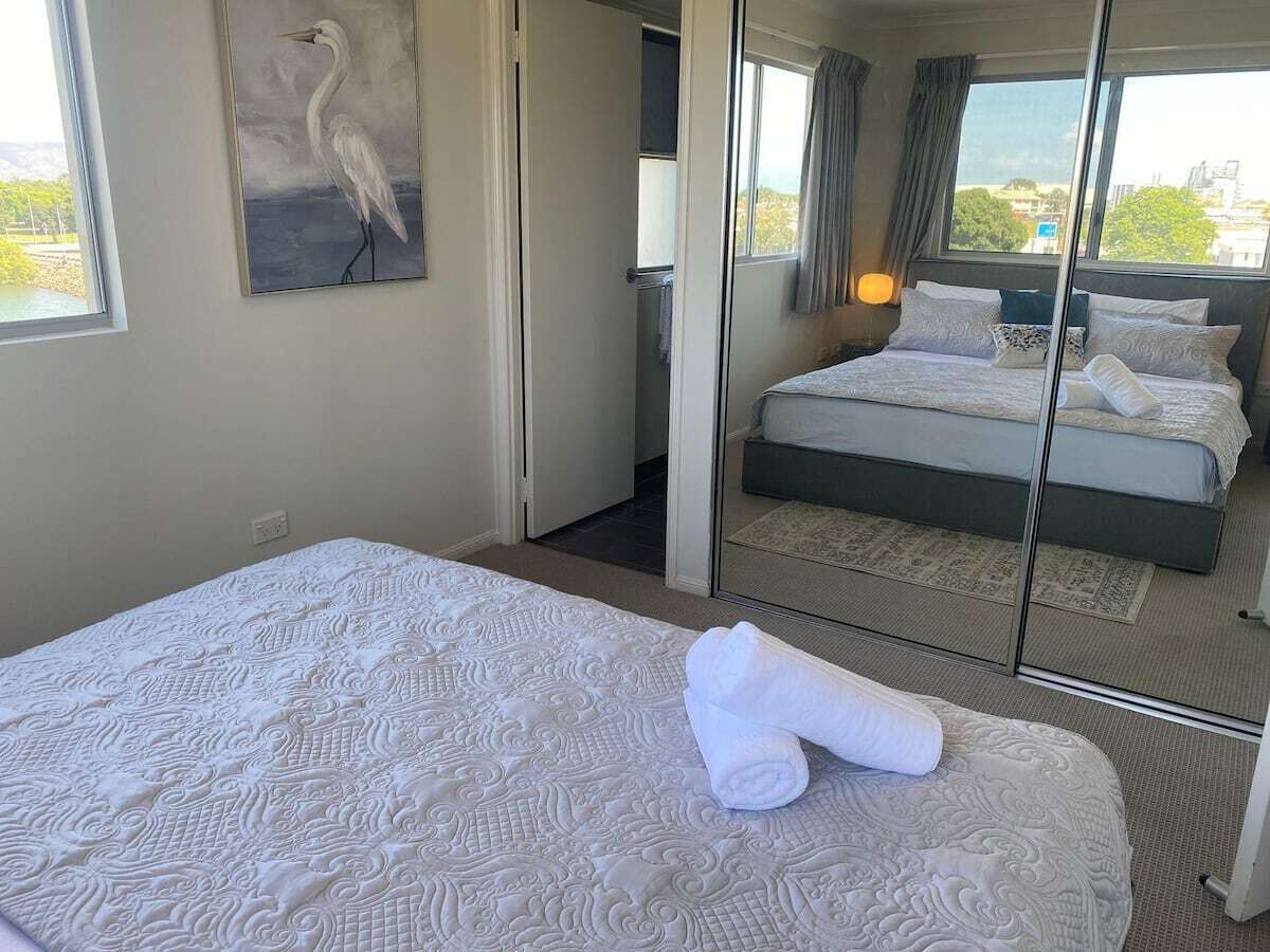 A hotel room with a large bed, a mirror, and a painting of a bird on the wall.
