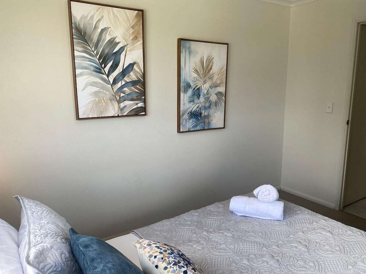 Une chambre d’hôtel avec un lit, des oreillers, une télécommande et des œuvres d’art accrochées au mur.