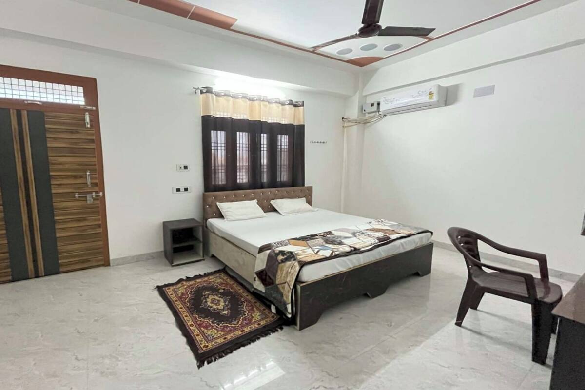 A bedroom with a bed, a desk, a chair, a wardrobe, and a ceiling fan.