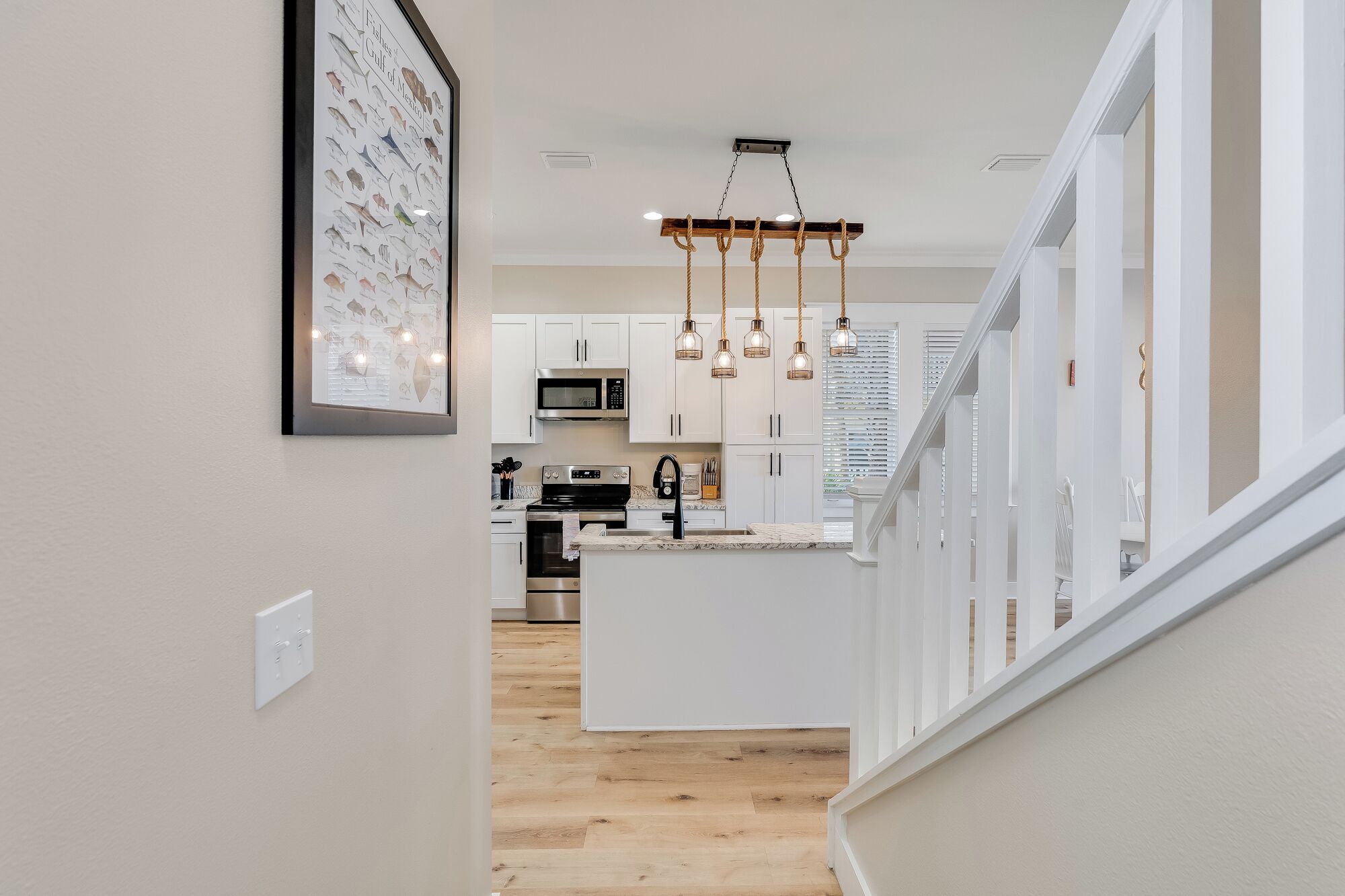 A modern kitchen with white cabinetry, a central island, and pendant lighting.