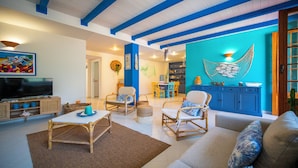 Ein Wohnzimmer mit Korbmöbeln, einem Fernseher und einer blauen Akzentwand.
