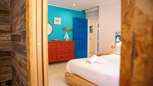Ein Schlafzimmer mit einem Bett, einem Schminktisch, einer blauen Tür und einer Wanduhr.