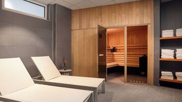 Un moderno cuarto de spa con dos sillones reclinables, una sauna de madera y un estante con toallas.
