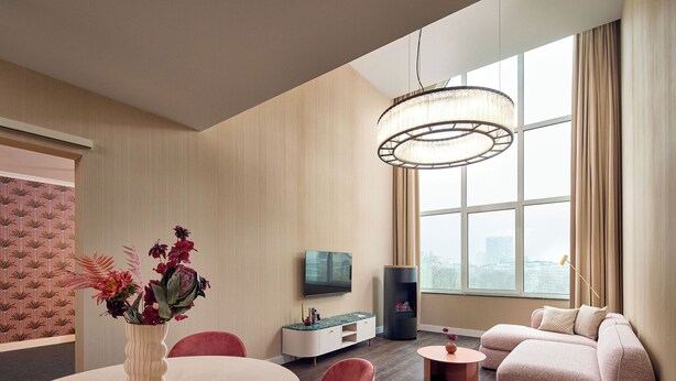 Una sala de estar moderna con una mesa redonda de comedor, un sofá, un televisor y un ventanal con vistas.