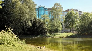 Un río con patos, árboles y un edificio que muestra 'PARK LATE' en la fachada.