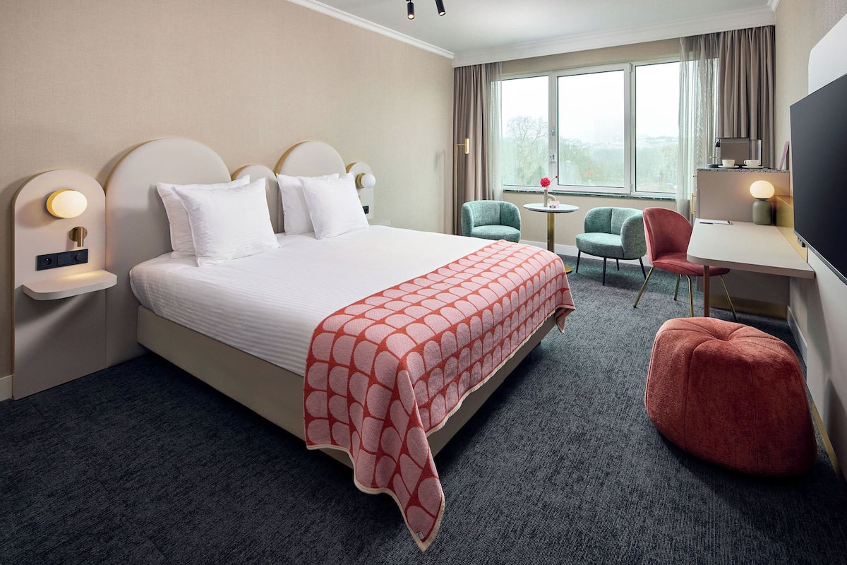 Une chambre d’hôtel avec un grand lit, un bureau, une chaise et un téléviseur.