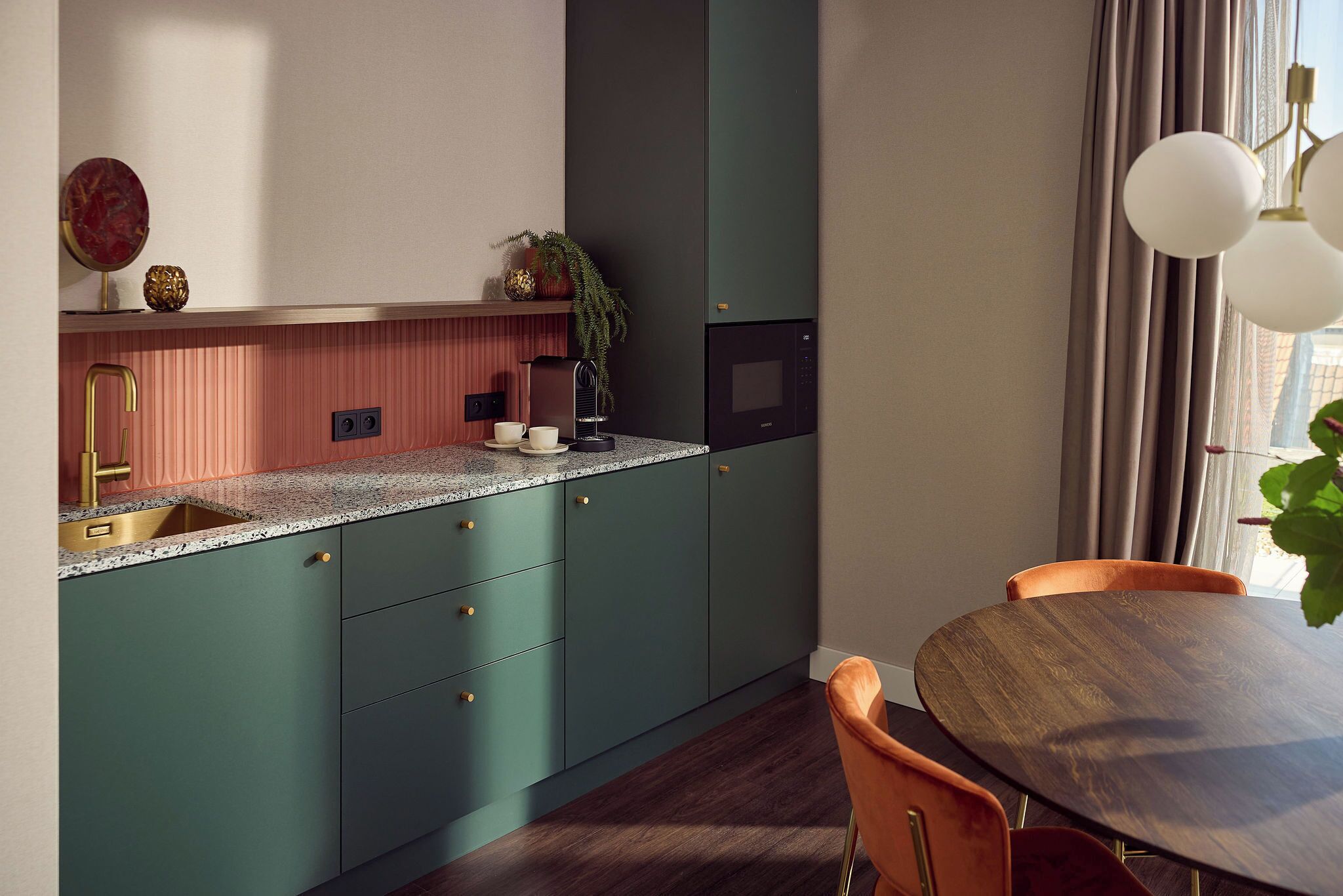 Una cocina moderna con armarios verde azulado, encimera de granito y mesa de comedor de madera.