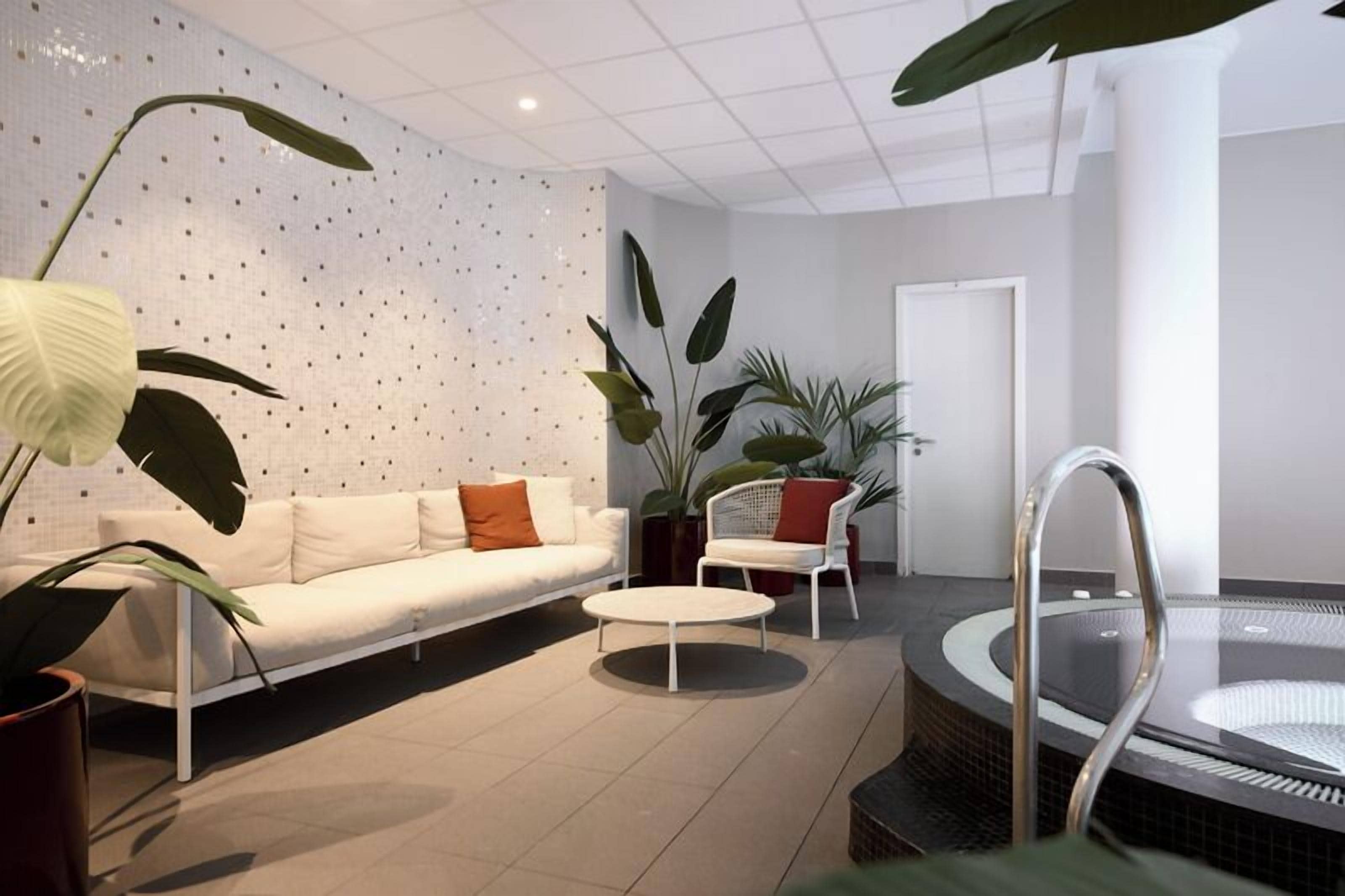 A modern indoor space with a white sofa, a round table, and a seating area with chairs.