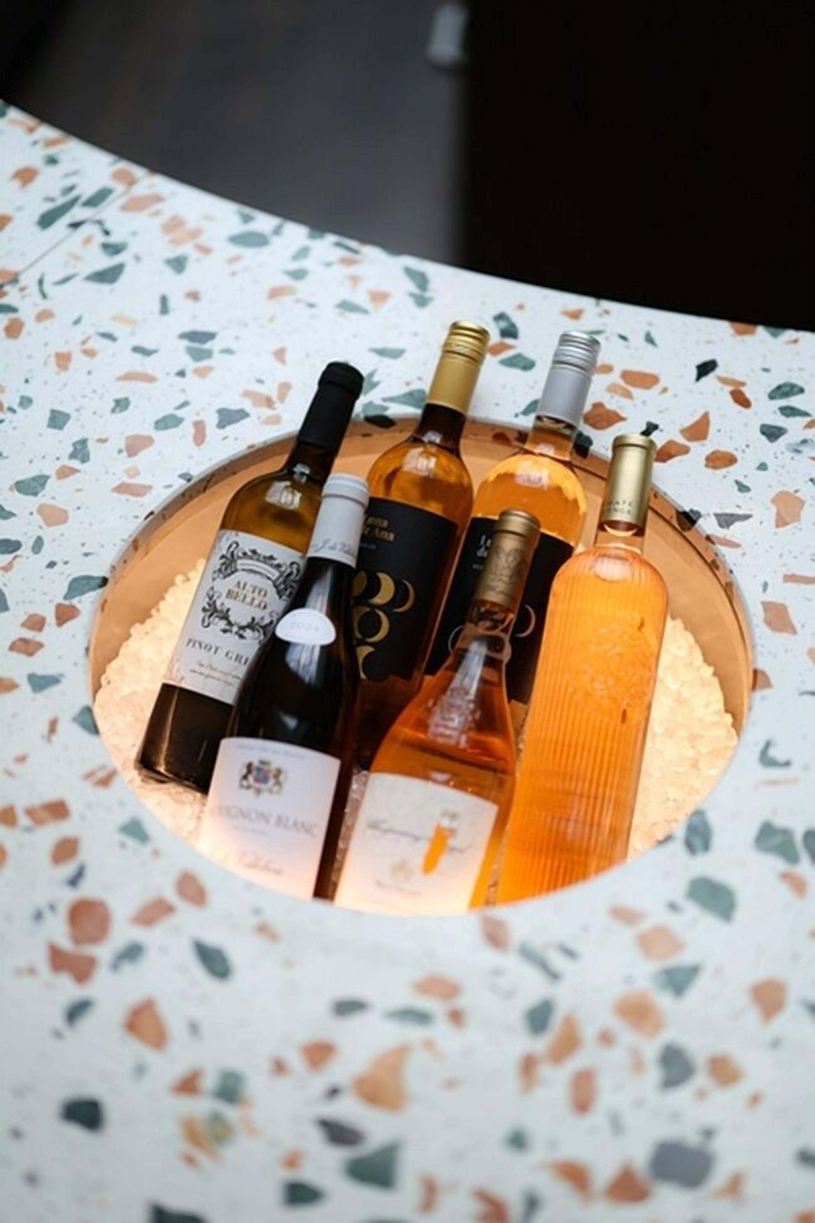 Une présentation circulaire de bouteilles de vin sur une table en terrazzo.