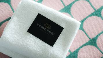 Een witte gevouwen handdoek met een zwart label op een gestreept kussen.