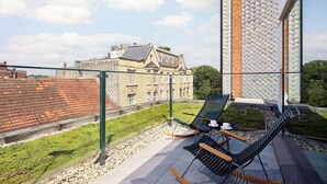 Terraza en la azotea con sillones de descanso y vistas a un edificio histórico.