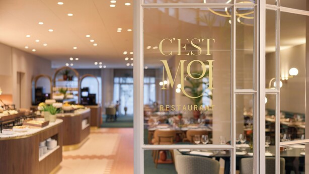 A restaurant interior with a buffet area, dining tables, and a glass wall displaying the restaurant's name.