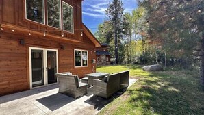 Een houten hut met een terras, straatmeubilair en een stenen open haard.