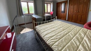 Un dormitorio con cama, escritorio, silla y armario.