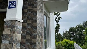 A building with a stone facade, a balcony with a white railing, and a sign indicating the number 102. - Eco Village (Vikasnagar)