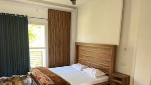 A bedroom with a wooden bed, a nightstand, and a wardrobe. - Eco Village (Vikasnagar)