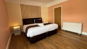 Ein Schlafzimmer mit einem Bett, Nachttischen, einem Heizkörper und einer Tür.
