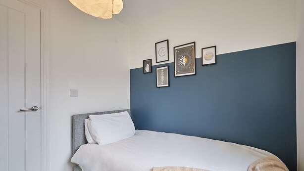 Une chambre à coucher avec un lit, une porte blanche et un mur orné de tableaux encadrés.