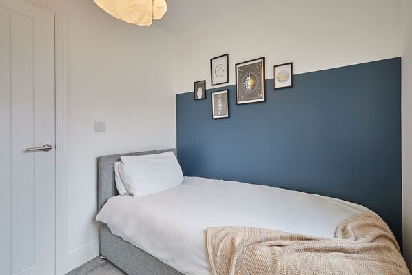 A bedroom with a bed, a white door, and a wall with framed pictures. - Host & Stay | Hewitt Close (Peterborough)