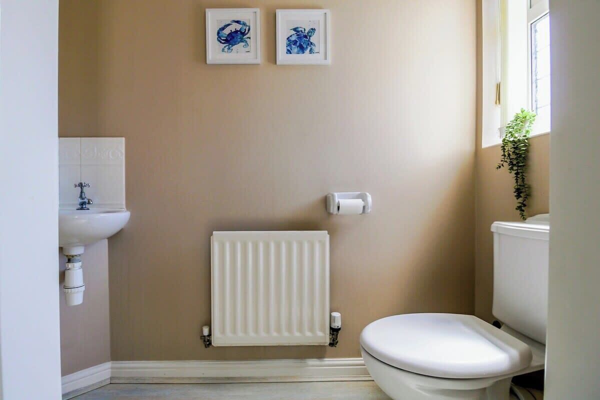 A bathroom with a white toilet, a white radiator, and a sink with a faucet.