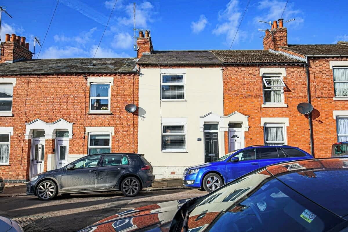 A row of terraced houses with cars parked in front.