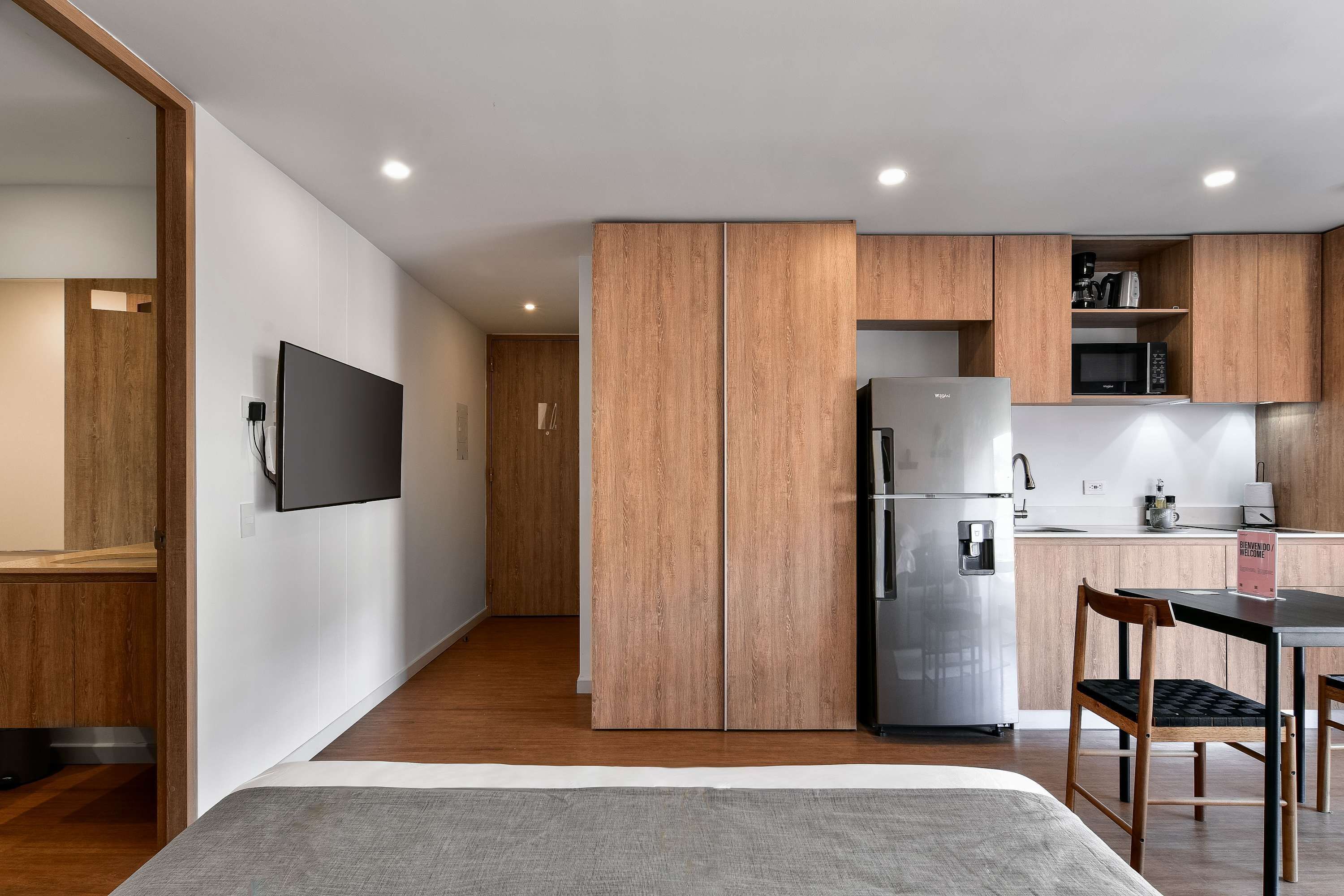 Eine moderne Küche mit Holzausstattung, einem Kühlschrank und einem Essbereich mit Tisch und Stühlen.
