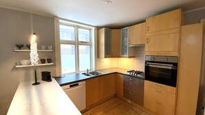 A modern kitchen with wooden cabinets, a built-in oven, and a window providing natural light. - Day Dream Vesturgata 5a (Reykjavik)