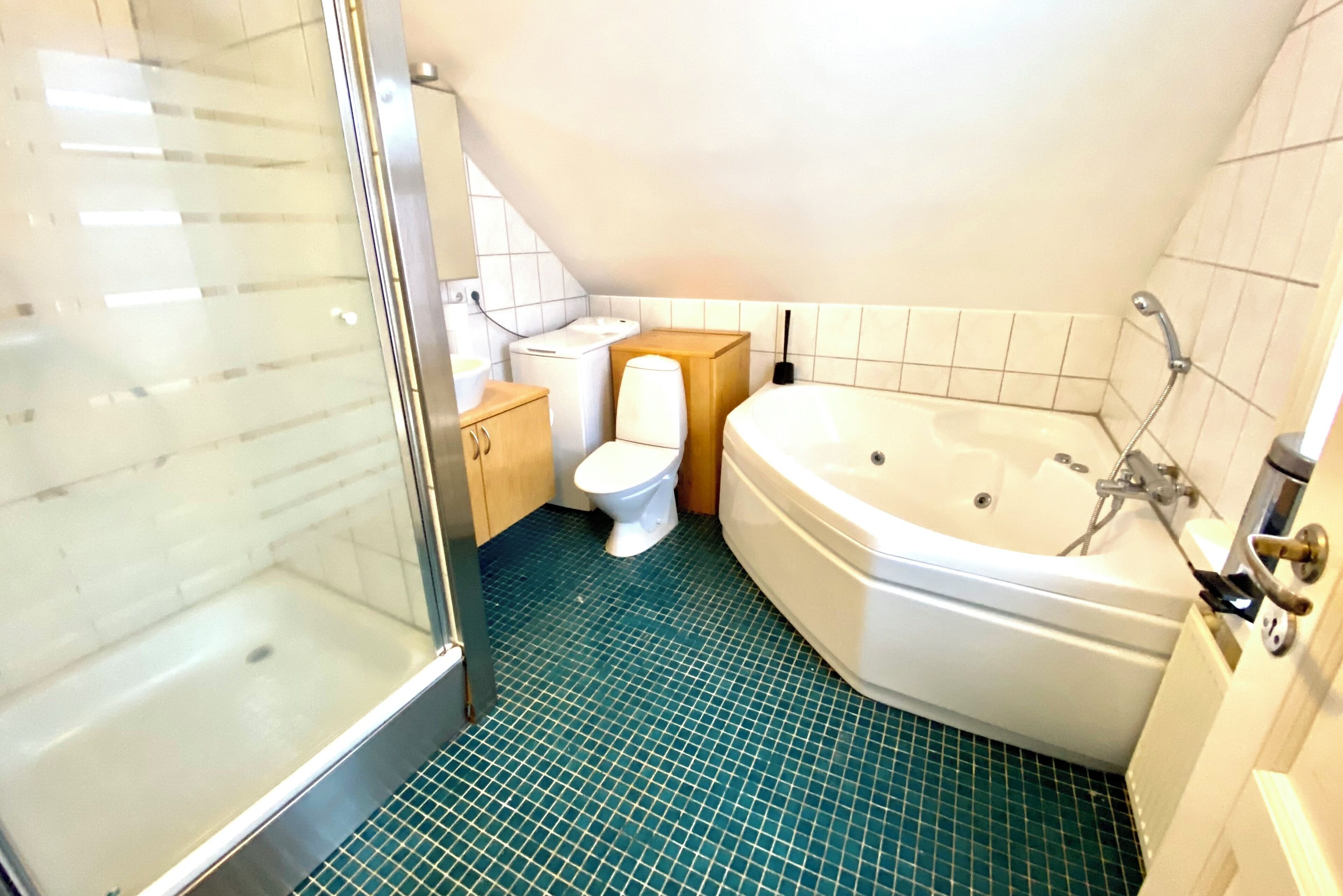 Un baño con cabina de ducha de vidrio, inodoro blanco, bañera y suelo de baldosas.