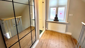 A room with a wooden floor, a window with a view, a radiator, and a hanging light fixture. - Day Dream Vesturgata 5a (Reykjavik)