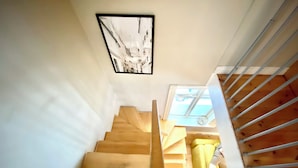 A wooden staircase with a handrail, a framed picture on the wall, and a window with a view of the outside. - Day Dream Vesturgata 5a (Reykjavik)