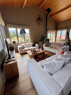 A spacious living room with a large sofa set, a wooden coffee table, and a television on a wooden stand.