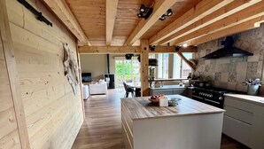 Een ruime keuken met houten balken, een groot kookeiland en uitzicht op het buiten.