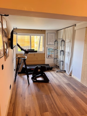 Uma academia em casa com esteira, bicicleta ergométrica e banco de musculação.