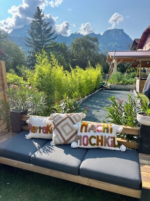 A garden with a wooden bench, potted plants, and a view of mountains.