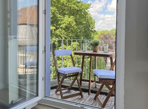 Un balcon avec deux chaises en bois, une petite table et un pot de fleurs.