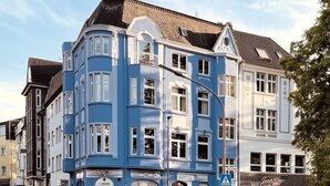 A blue building with multiple windows and a sign for 'Veltrins'.