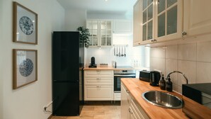 A modern kitchen with white cabinets, a black refrigerator, and a wooden countertop.