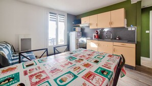 Cocina compacta con comedor, que incluye una mesa con mantel de motivos de postres, un microondas y un refrigerador.